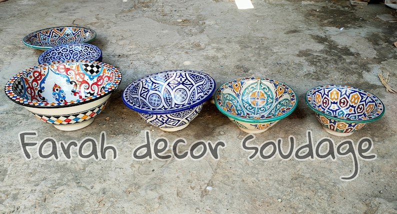 May include: Five ceramic bowls with intricate colourful patterns. The bowls are arranged in a row on a grey concrete surface. The text "Farah decor soudage" is written below the bowls.