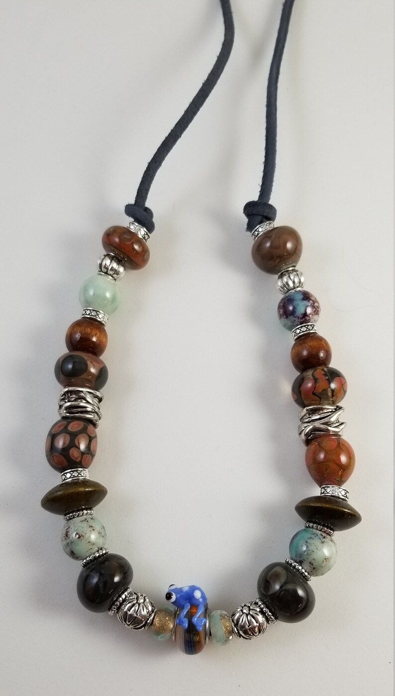 Frog bead necklace with handblown glass ceramic and wood beads on blue gray blue suede leather cord with a heart lobster claw clasp.