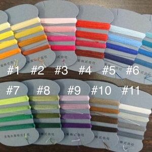 May include: A set of 11 spools of embroidery floss, each with a different colour. The spools are labelled with numbers 1 through 11. The colours are: yellow, orange, pink, red, light blue, dark blue, green, light green, purple, brown, and white.
