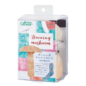 Puede incluir: Una herramienta de madera en forma de hongo para zurcir, en un paquete de plástico transparente. El paquete tiene un logotipo de trébol verde y el texto "Darning mushroom" y "Clover".
