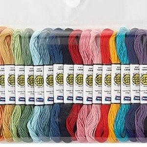 Könnte beinhalten: Eine Sammlung von Stickgarn in einer transparenten Plastikverpackung. Das Garn ist in verschiedenen Farben erhältlich, darunter Weiß, Orange, Gelb, Grün, Blau, Rot, Rosa und Schwarz. Jede Spule hat ein Etikett mit japanischem Text.