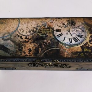 May include: Wooden box with a steampunk design featuring clock faces and gears. The box has a hinged lid and a metal clasp. The top of the box has a vintage-style print with clock faces and gears.