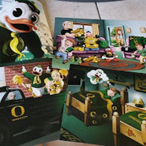 May include: Set of four green and yellow cartoon illustrations featuring the University of Oregon mascot, the Duck. The illustrations depict the Duck in various scenes, including a family gathering, a car ride, and a dream sequence.