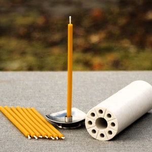 May include: A set of yellow beeswax candles with a white wick, a metal candle holder, and a white ceramic candle holder with multiple holes.