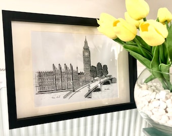 Könnte beinhalten: Schwarz-weiß-Zeichnung der Houses of Parliament und Big Ben in London, gerahmt in einem schwarzen Rahmen. Die Zeichnung ist auf weißem Hintergrund und hängt an einer Wand.