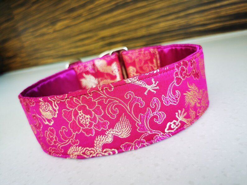 May include: A pink dog collar with a gold floral and dragon pattern.