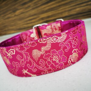 May include: A pink and gold dog collar with a floral pattern. The collar is made of a soft, durable fabric and features a secure buckle closure.