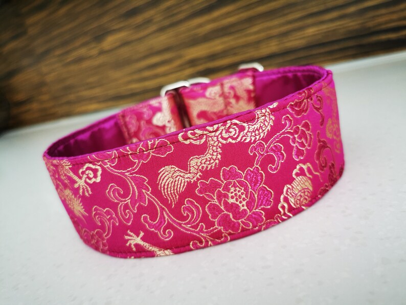 May include: A pink and gold dog collar with a floral pattern. The collar is made of a soft, durable fabric and features a secure buckle closure.