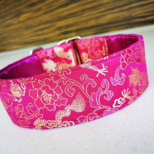 May include: A pink and gold dog collar with a floral and dragon pattern.