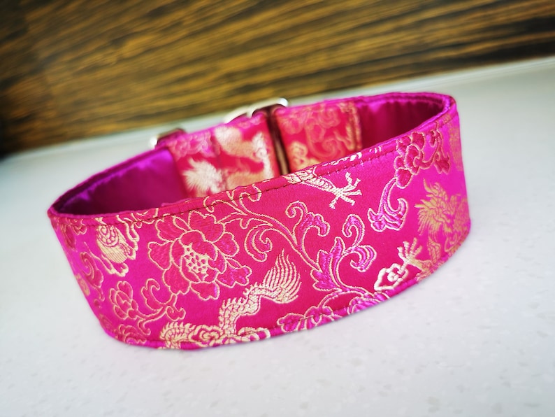 May include: A pink and gold dog collar with a floral and dragon pattern.