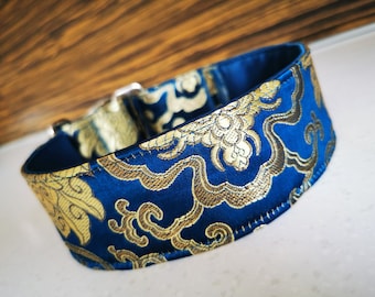 Puede incluir: Un collar para perro azul y dorado con estampado y hebilla plateada. El collar está hecho de una tela suave y lujosa.