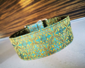 Könnte beinhalten: Ein Hundehalsband mit teal- und goldfarbenem Muster und einer dekorativen Schnalle.