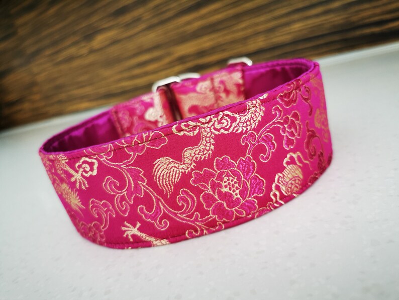 May include: A pink and gold dog collar with a floral pattern. The collar is made of a soft, luxurious fabric and features a silver buckle.