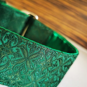 May include: A green dog collar with a patterned design. The collar is made of a soft, durable material and has a secure buckle closure.