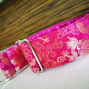 May include: A pink dog collar with a gold dragon and floral pattern.