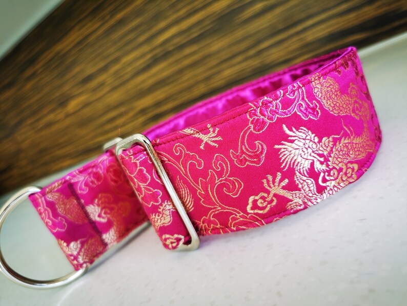 May include: A pink dog collar with a gold dragon and floral pattern.