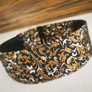Puede incluir: Un collar de perro negro, dorado y blanco con un dise&ntilde;o floral.