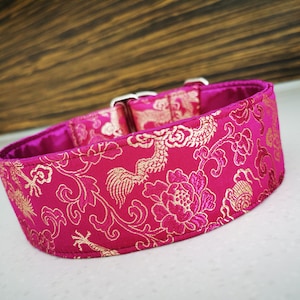 May include: A pink and gold dog collar with a floral pattern. The collar is made of a soft, luxurious fabric and features a silver buckle.