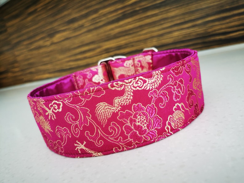 May include: A pink and gold dog collar with a floral pattern. The collar is made of a soft, luxurious fabric and features a silver buckle.