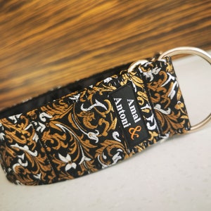 Puede incluir: Collar para perro de patr&oacute;n negro y dorado con un anillo en D plateado y el texto "Amal & Antoni" en una etiqueta negra.