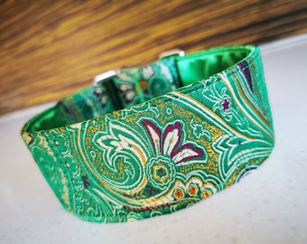 May include: A green paisley dog collar with a vibrant pattern of white, gold, and burgundy floral elements. The collar has a satin lining and silver-colored metal hardware.