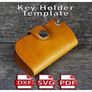 May include: A tan leather key holder with a silver metal snap closure and key ring. The text "Key Holder Template" is at the top. Below are icons for DXF, SVG, and PDF file formats.