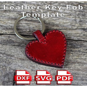 May include: A red heart-shaped leather key fob template with a silver keyring. The leather is stitched with dark thread. The text "Leather Key Fob Template" is at the top. Below are DXF, SVG, and PDF file icons.