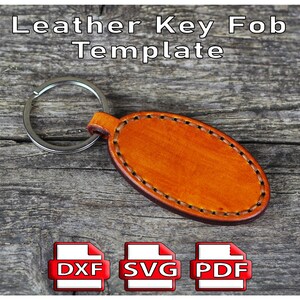 May include: An oval-shaped, brown leather key fob template with a silver key ring. The leather is stitched around the edges. The text "Leather Key Fob Template" is at the top. Below are icons labeled DXF, SVG, and PDF.