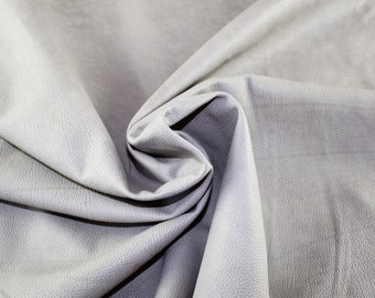 May include: Close-up of a light gray textured fabric with a soft, smooth feel. The fabric is folded and draped, showcasing its texture and drape.