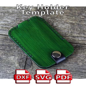 May include: A green key holder template with a button closure, black stitching, and the text "Key Holder Template." Includes DXF, SVG, and PDF file icons.