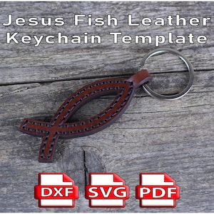 May include: A brown leather keychain in the shape of a fish, with the text "Jesus Fish Leather Keychain Template". The keychain has a silver ring and is on a wooden surface. Includes DXF, SVG, and PDF file icons.