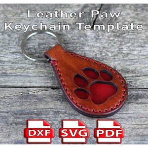 Könnte beinhalten: Braune Leder-Schlüsselanhänger-Vorlage mit rotem Pfotenabdruck und Metallring. Der Schlüsselanhänger hat rote Nähte. Der Text "Leather Paw Keychain Template" ist oben zu sehen. DXF-, SVG- und PDF-Symbole sind ebenfalls abgebildet.