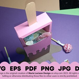 May include: A pink and brown popsicle shaped box with a clear window filled with colorful candy. The box is sitting on a brown surface with a purple background. The text "SVG EPS PDF PNG JPG DXF" is at the bottom of the image.