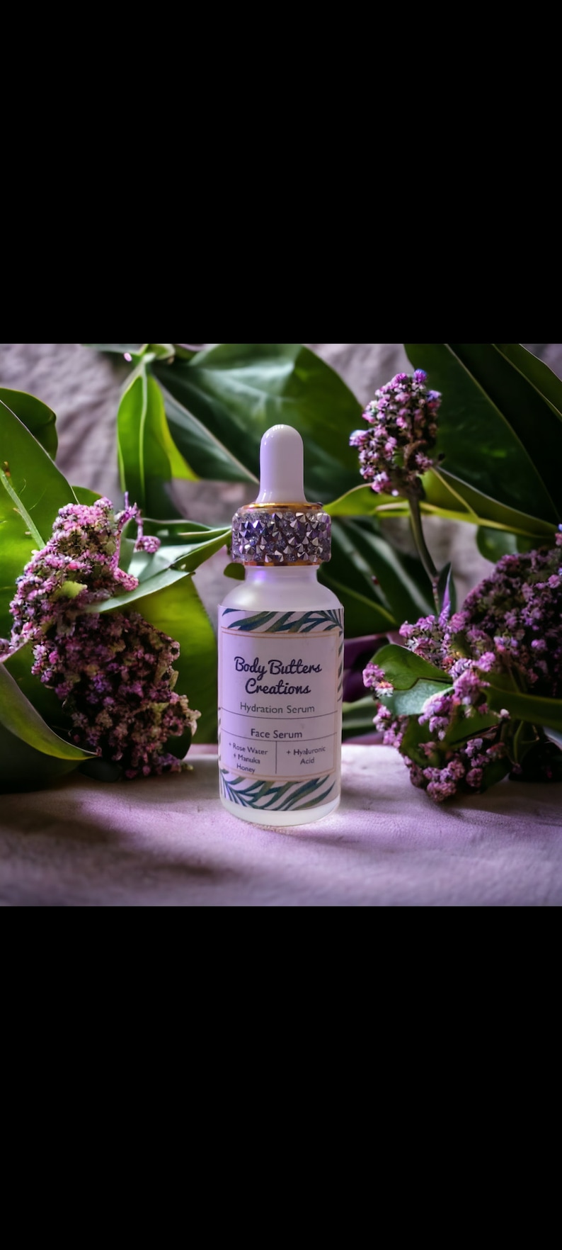 Może przedstawiać: Przezroczysta butelka szklana z pozłacanym i srebrnym korkiem, z etykietą "Body Butters Creations Serum nawilżające Serum do twarzy Woda r&oacute;żana + Mi&oacute;d marula + Kwas hialuronowy".
