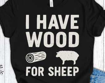 Op de afbeelding: Zwart t-shirt met de witte tekst "I HAVE WOOD FOR SHEEP". Het ontwerp bevat een boomstam en een schapensilhouet. Dit shirt van zacht materiaal is geschikt voor dagelijks gebruik.
