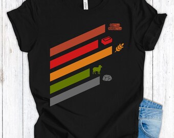 Op de afbeelding: Zwart t-shirt met een kleurrijk grafisch ontwerp. Het ontwerp heeft diagonale strepen in tinten oranje, rood en groen, met iconen van boomstammen, een baksteen, tarwe, een schaap en een steen. Het shirt is gemaakt van zacht materiaal.