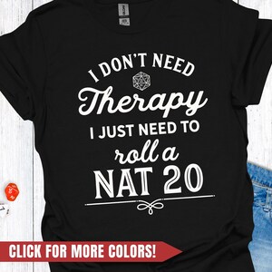 Op de afbeelding: Zwart T-shirt met witte tekst: "I DON'T NEED Therapy I JUST NEED TO roll a NAT 20." Het ontwerp bevat een D20 dobbelsteenafbeelding. Een rode banner onderaan zegt "CLICK FOR MORE COLORS!"