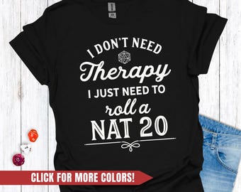 Op de afbeelding: Zwart T-shirt met witte tekst: "I DON'T NEED Therapy I JUST NEED TO roll a NAT 20." Het ontwerp bevat een D20 dobbelsteenafbeelding. Een rode banner onderaan zegt "CLICK FOR MORE COLORS!"