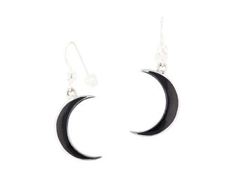 May include: A pair of silver crescent moon earrings with black enamel. The earrings have a hook closure.