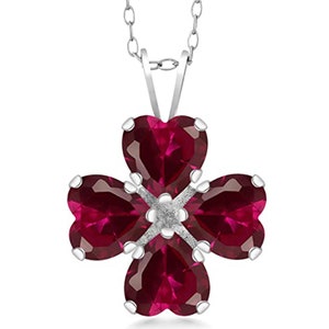 May include: A silver necklace with a four-leaf clover pendant featuring four red heart-shaped gemstones.