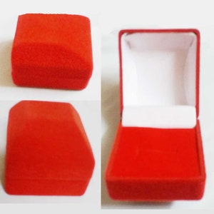 May include: A red velvet ring box, closed and open, against a white background. The closed box is a square shape with rounded edges. The open box reveals a white interior and a slot for a ring.