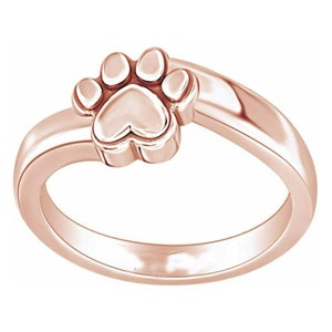 Puede incluir: Un anillo de oro rosa con un diseño de huella de pata. El anillo es simple y elegante, lo que lo convierte en un regalo perfecto para cualquier amante de las mascotas.