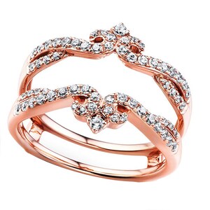 May include: Rose gold ring guard with a double band design. The ring features a series of small, sparkling diamonds set along the bands and in decorative floral-like clusters. The ring is designed to enhance the look of a solitaire ring.