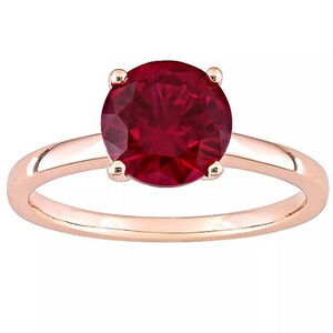 Pode incluir: Um anel de ouro rosa com uma grande gema de rubi vermelha redonda.