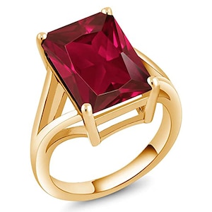 Puede incluir: Un anillo de oro con una gran piedra preciosa roja de talla esmeralda.