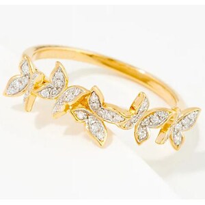 Puede incluir: Un anillo de oro con un delicado diseño de cuatro mariposas engastadas con piedras blancas brillantes.