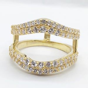 May include: A gold ring with a double row of small clear stones. The ring is designed to be worn as a wedding band enhancer.