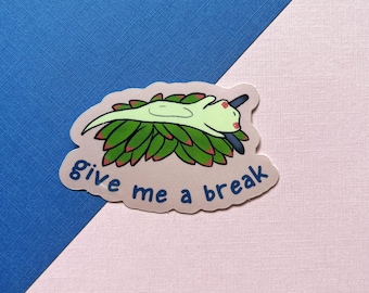 May include: A sticker with a cartoon sea slug lying on a bed of green seaweed. The sticker has the text "give me a break" in blue.