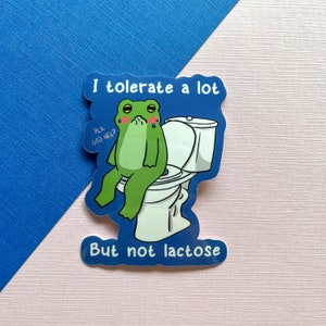 Pu&ograve; includere: Un adesivo blu con una rana di cartone animato seduta su un water. La rana &egrave; verde e ha un'espressione triste. L'adesivo dice "Toller&ograve; molto ma non il lattosio".
