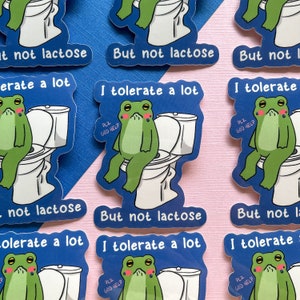 Pu&ograve; includere: Un set di otto adesivi a tema rana con sfondo blu. Gli adesivi mostrano una rana seduta su un water con il testo "Toller&ograve; molto, ma non il lattosio" e "PLZ GOD HELP".